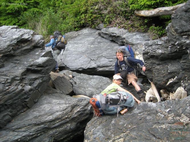 man on the other side of rocks while lady and second man climb over boulders to get to the other side