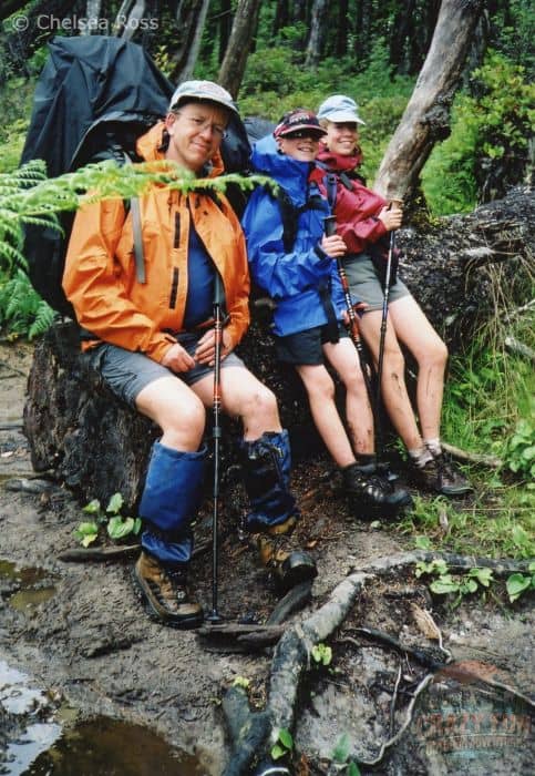 A man, boy and girl sitting on a log.