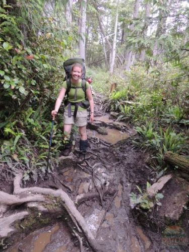 Lady walking on roots and in mud while backpacking the West Coast Trail.
