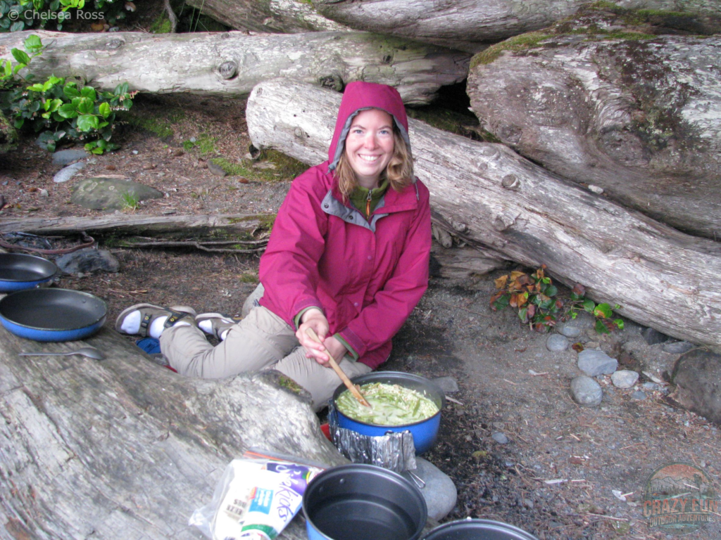 West Coast Trail tips: Share the load. A lady is sitting on the sand making supper.
