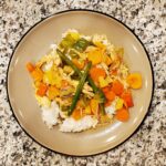 Pineaple Chicken Stirfy with peppers on top of white rice on a plate