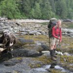 West Coast Trail tips are here to help you plan your trip. A girl is standing on green algae as she walks on the beach.