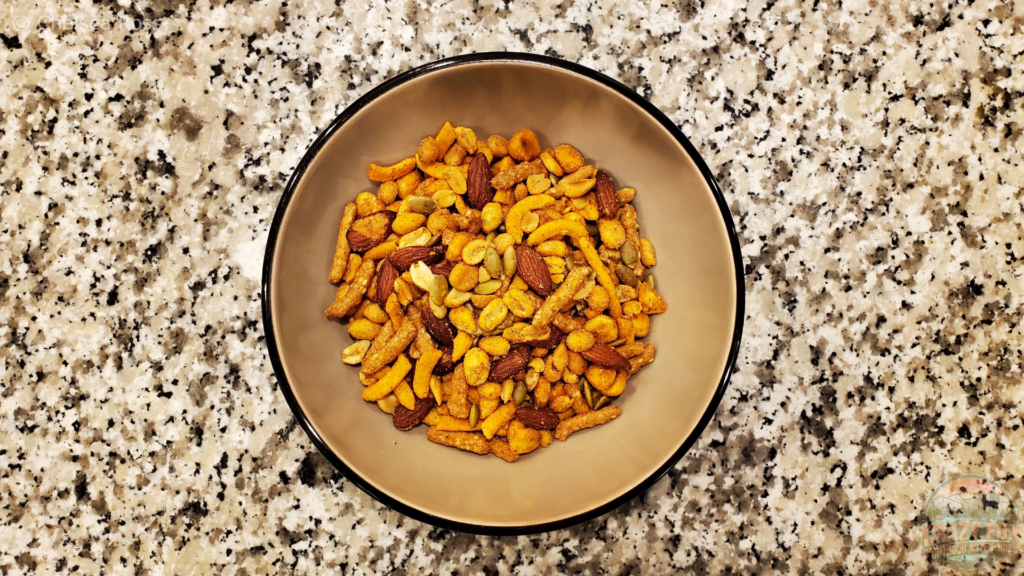 Texas Cajun Mix containing almonds, pumpkin seeds, corn, peanuts and sesame seeds in a tan bowl on a marble countertop are last on the list of 6 easy snack ideas for kayaking trips.