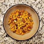 Texas Cajun Mix containing almonds, pumpkin seeds, corn, peanuts and sesame seeds in a tan bowl on a marble countertop are last on the list of 5 easy snack ideas for your kayaking trip.