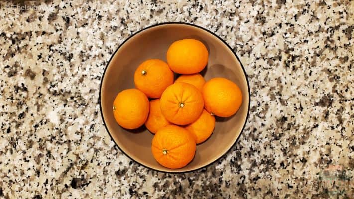 Mandarin oranges sitting in a tan bowl on a marble countertop are easy snack ideas for kayaking.