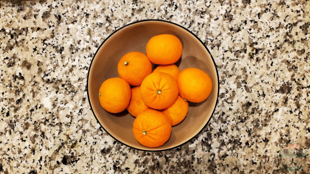 Mandarin oranges sitting in a tan bowl on a marble countertop are first on the list of 6 easy snack ideas for kayaking trips.