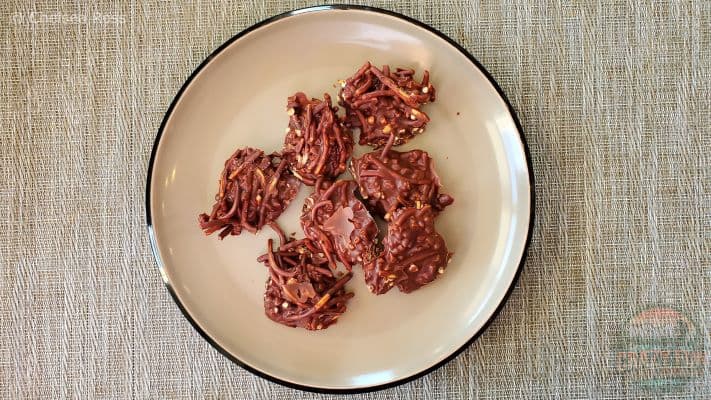 Chow Mein Chocolate clumps made from chow mein noodles, peanuts, butterscotch and chocolate chips sit on a plate. 