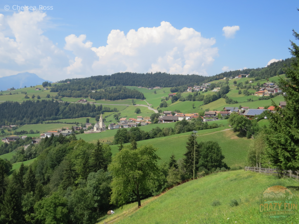 Looking towards Mölten, a German village in northern Italy.  Farms can be seen all around the village and they are separated with green trees on our unforgettable hiking holiday in Bolzano.