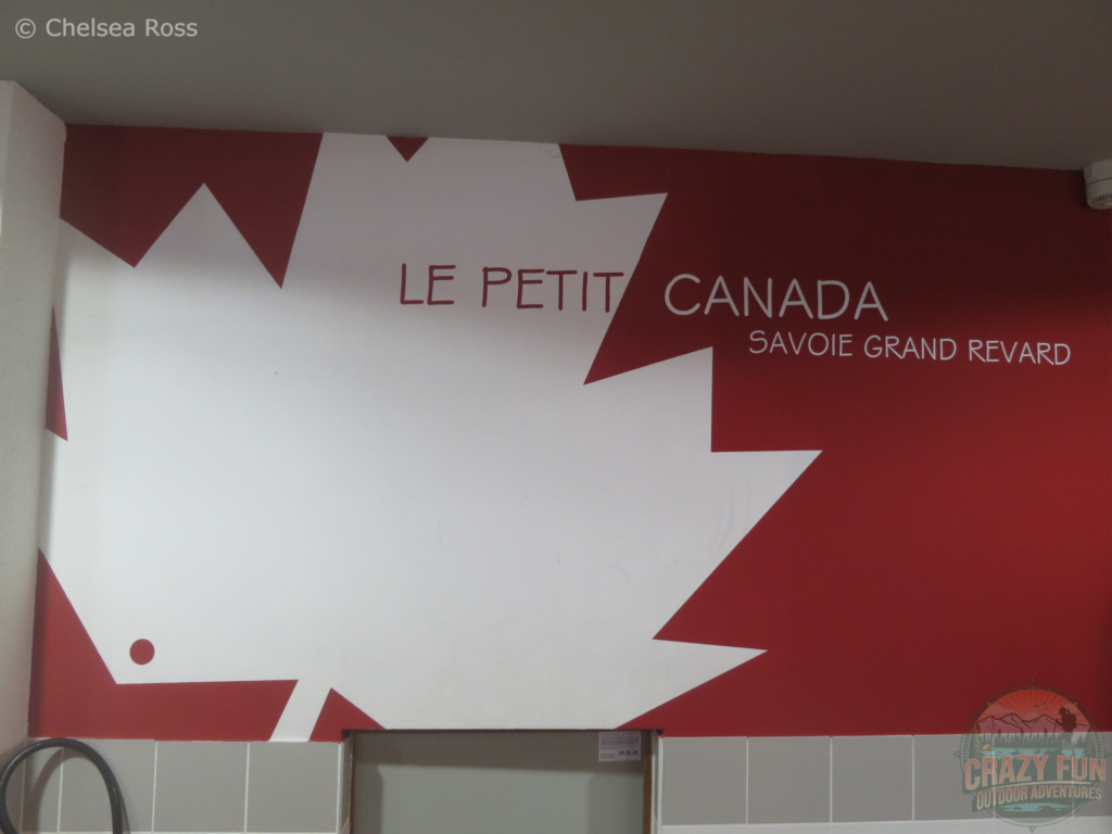 Le Petit Canada: Savoie Grand Revard sign in the tourism center. It shows the Canadian white maple leaf with red surrounding it. It represents little Canada because it reminds them of Canada's landscapes while cross-country skiing in La Féclaz.