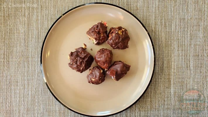 Chocolate Peanut Butter Balls made from peanut butter, chocolate and butter sit on a plate. 