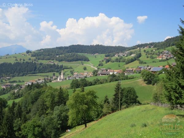 Looking towards Mölten, a German village in northern Italy. Farms can be seen all around the village and they are separated with green trees on our unforgettable hiking holiday in Bolzano.