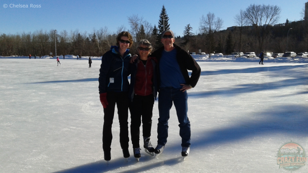 My parents and I smiling to take a picture while standing on Victoria Park skating oval. It's a gorgeous blue sky day with nice ice. It is the second of 5 Awesome Outdoor Skating Rinks in Alberta.