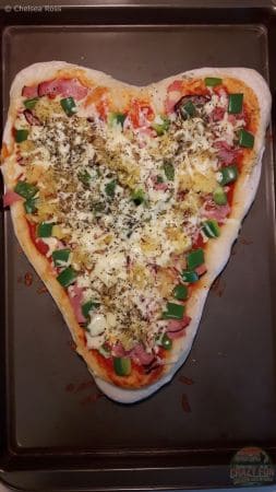 Couple made a heart pizza for Valentine's Day with ham, pineapple, green peppers and lots of cheese. 