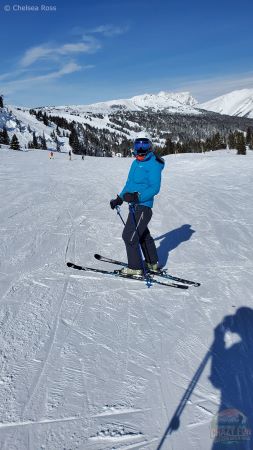 Lady wearing a blue coat, navy pants to keep warm on a cold windy day while downhill skiing. 