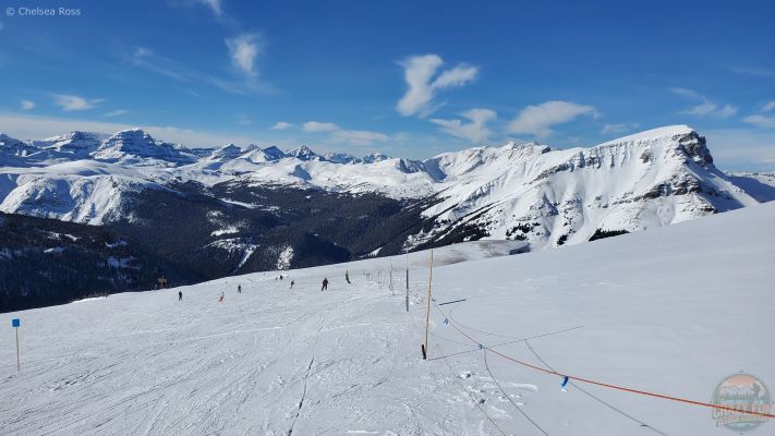 A spectacular view of mountains in the background showing a windy but sunny and blue sky day. 