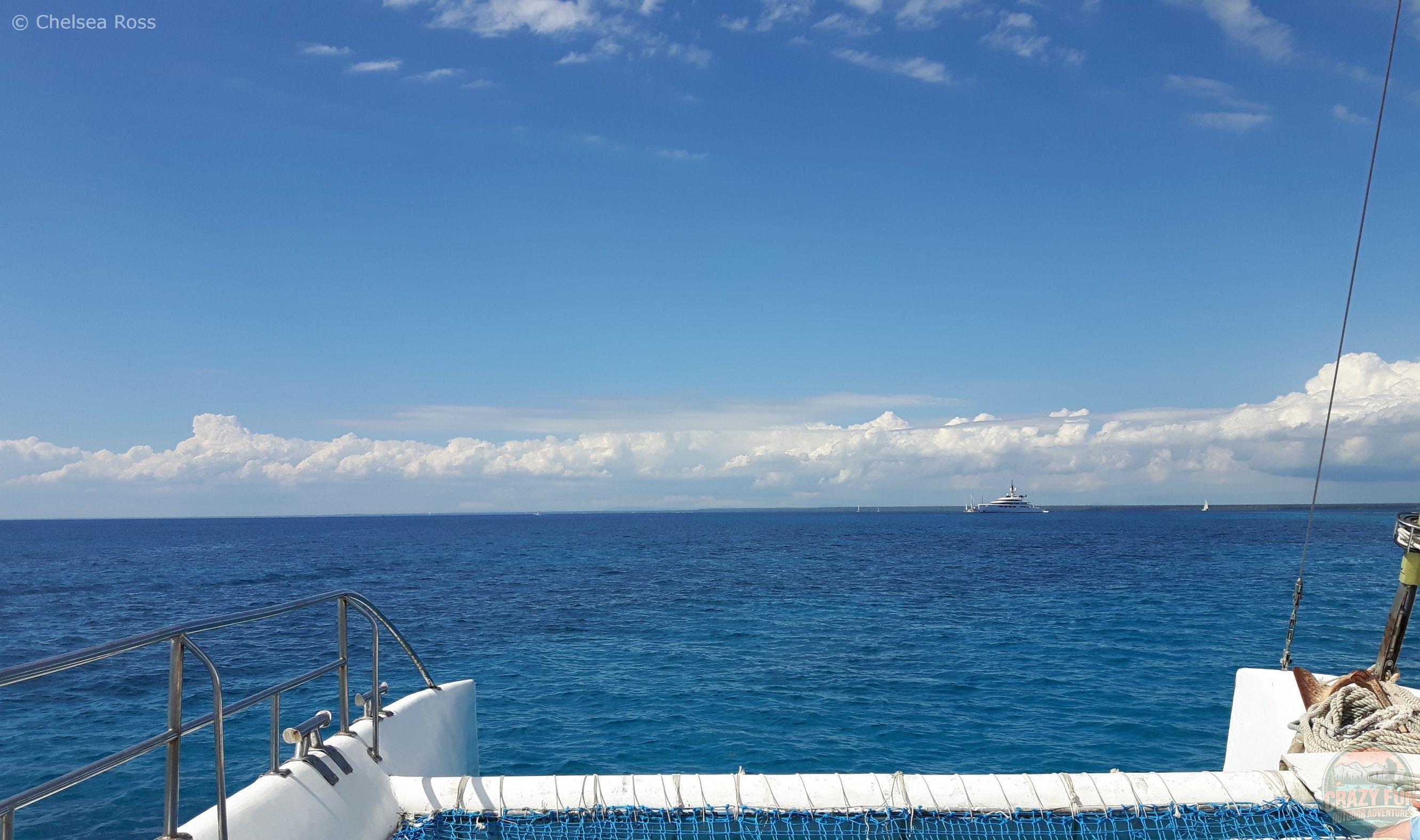 Top 10 Activities from Majestic Resorts: catamaran experience is next. Showing the edge of the catamaran with the blue ocean in front of us and clouds in the distance.