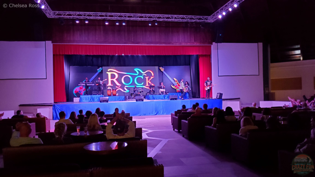 Top 10 Activities from Majestic Resorts: outdoor nightly concerts is next. Rock is shown on the stage while musicians play music. The audience can be seen in the shot in front of the stage.