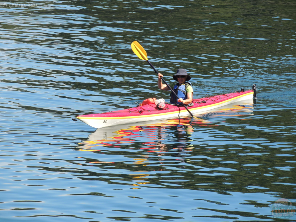 My mom is kayaking in her red kayak. Her clear Nalgene bottle is sitting in front of her, easily accessible. 