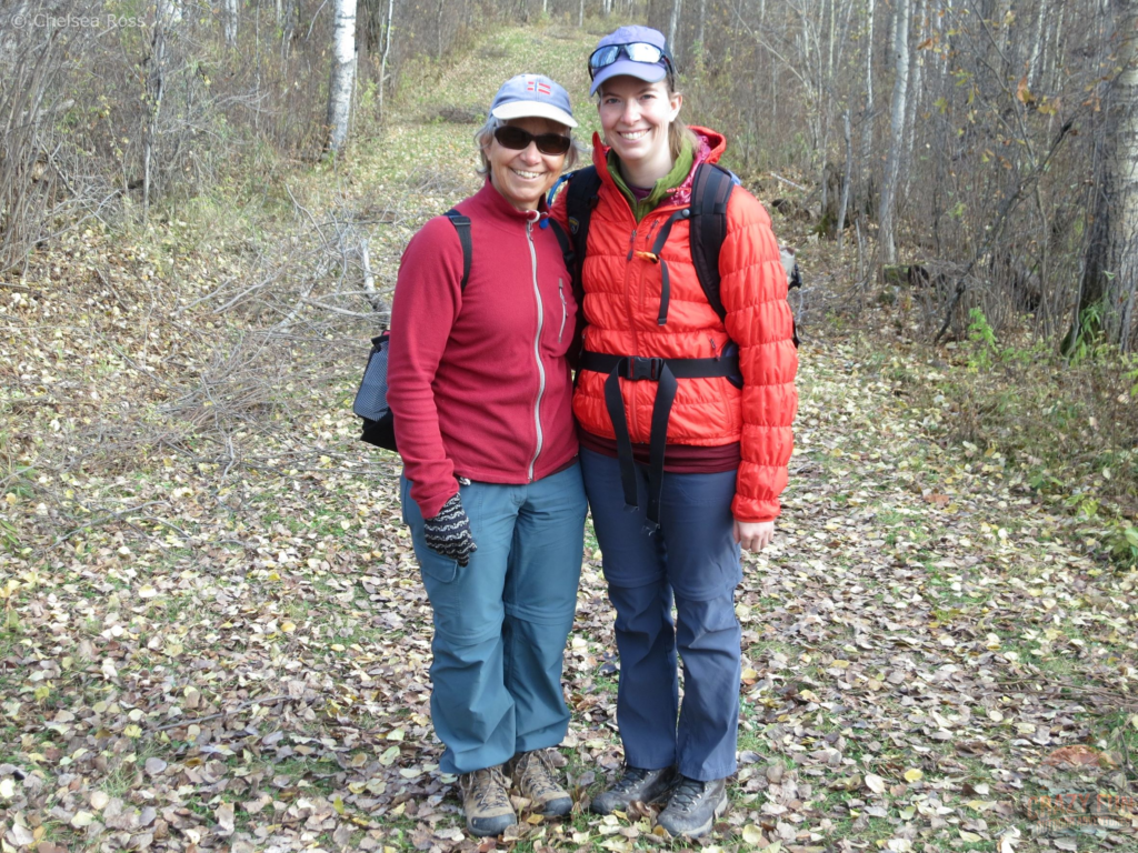 Mom and I standing on a trail on a fall day. My mom is wearing a red fleece while I'm wearing an orange coat with a backpack. We are both wearing zip-off pants for number seven of 15 Awesome Kayaking Gifts for Moms.