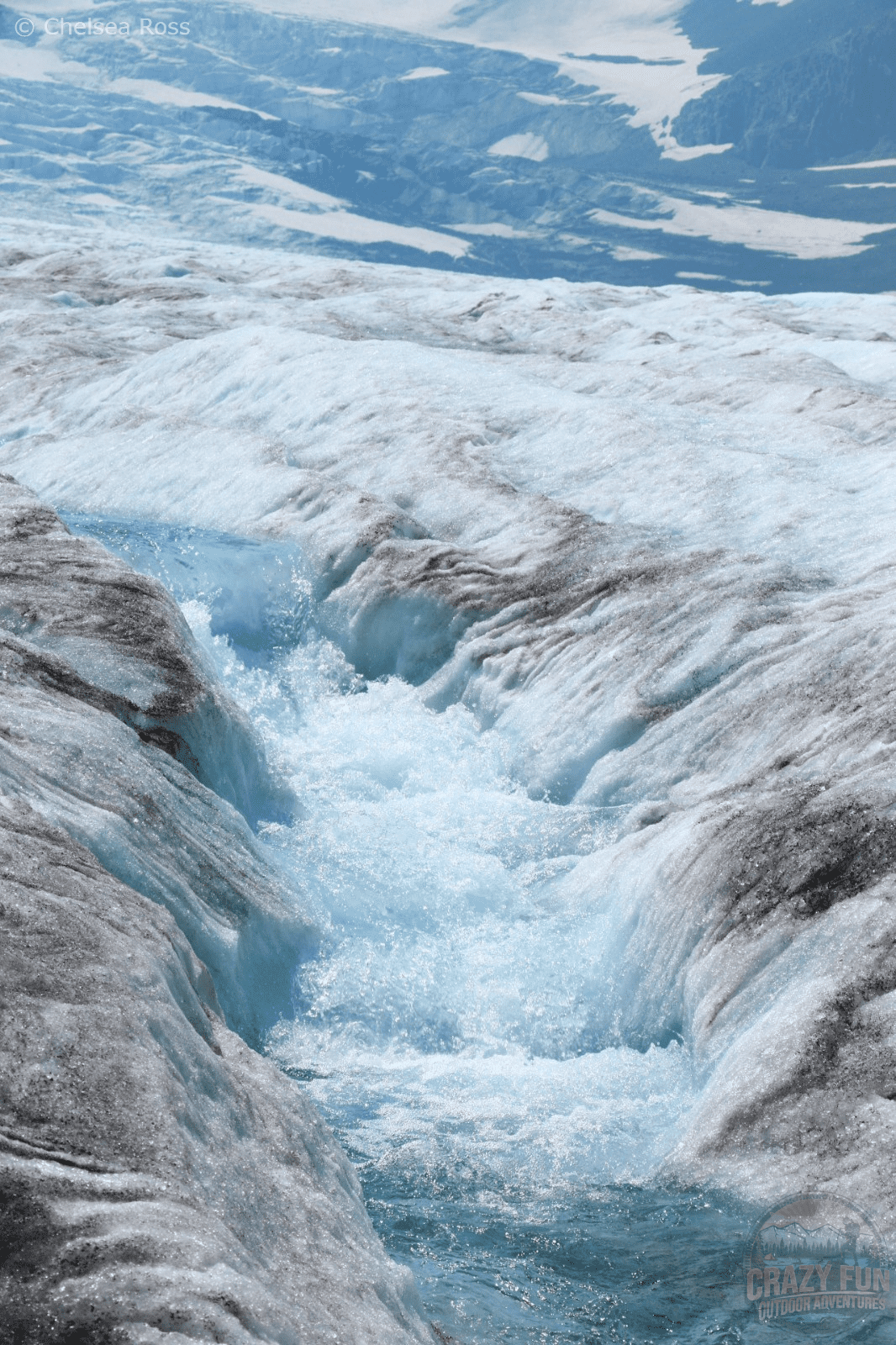 Large volume of water washing down the glacier in river form.
