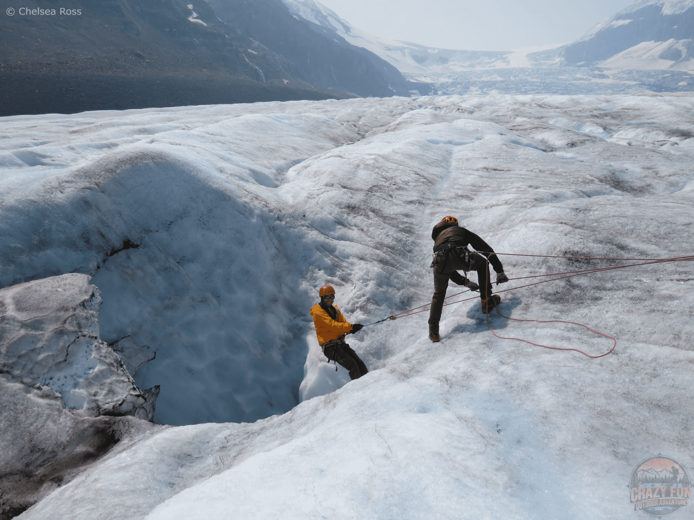 Kris descending into Athabasca Glacier while the guide helps guide him down. The glacier can be seen around him.