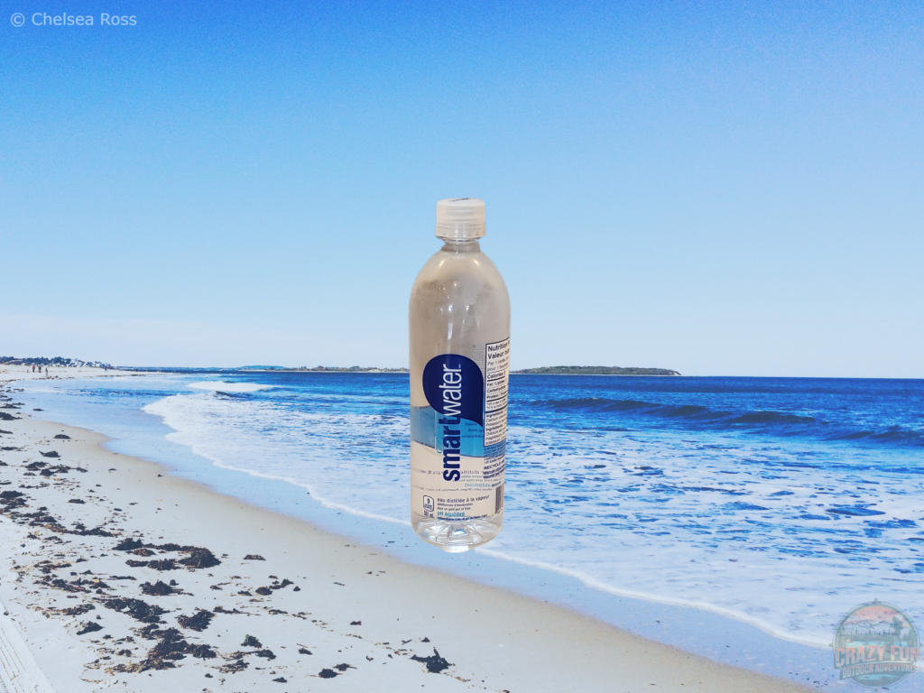 A picture of a bottle of water with the beach as the background.