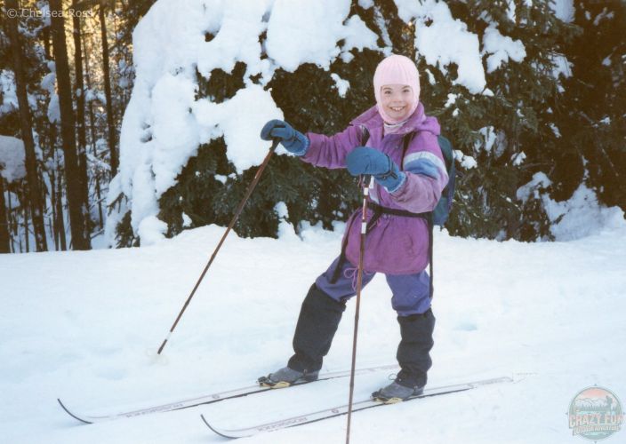 Girl at ten years old cross-country skiing in a purple coat.