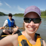 Devon to Edmonton canoe with Scott in the back and myself in the front on the North Saskatchewan. It's a gorgeous day with blue skies and trees on the side of the river.
