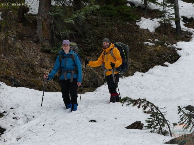 A couple walking down from the campsite in ankle-deep snow with our blue and yellow raincoats on.