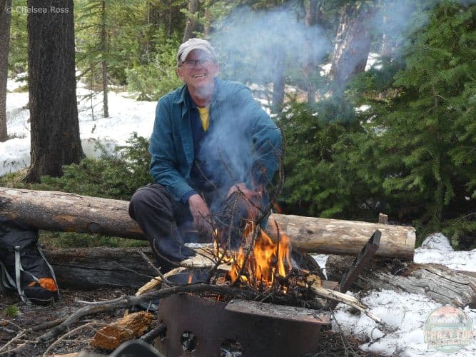 Man behind smoke from the campfire he built.