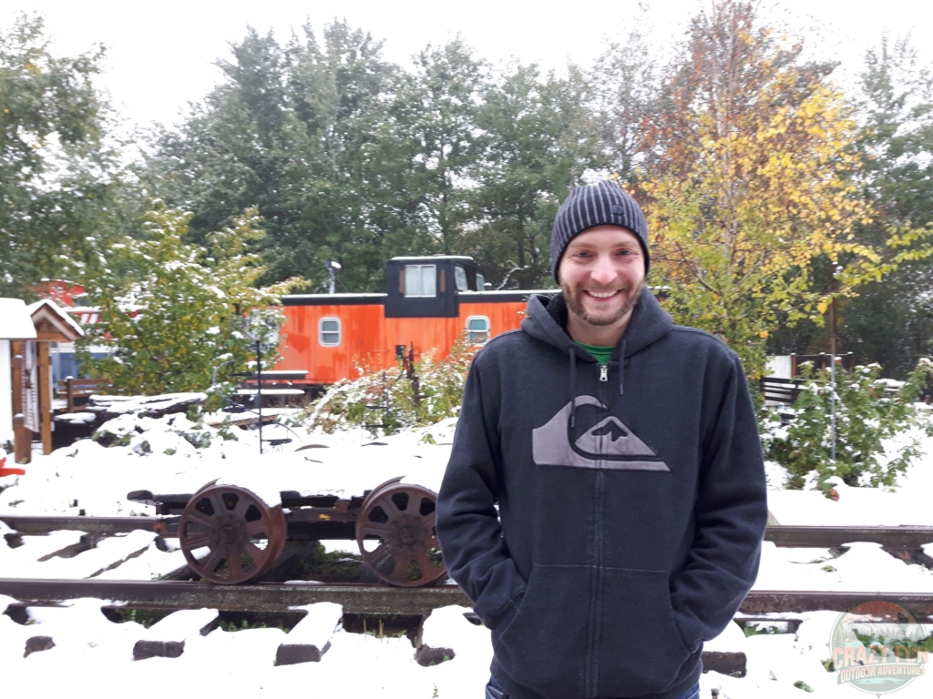 Edmonton Day Trips: Kris standing in his black fleece in front of an orange train with snow on the ground.