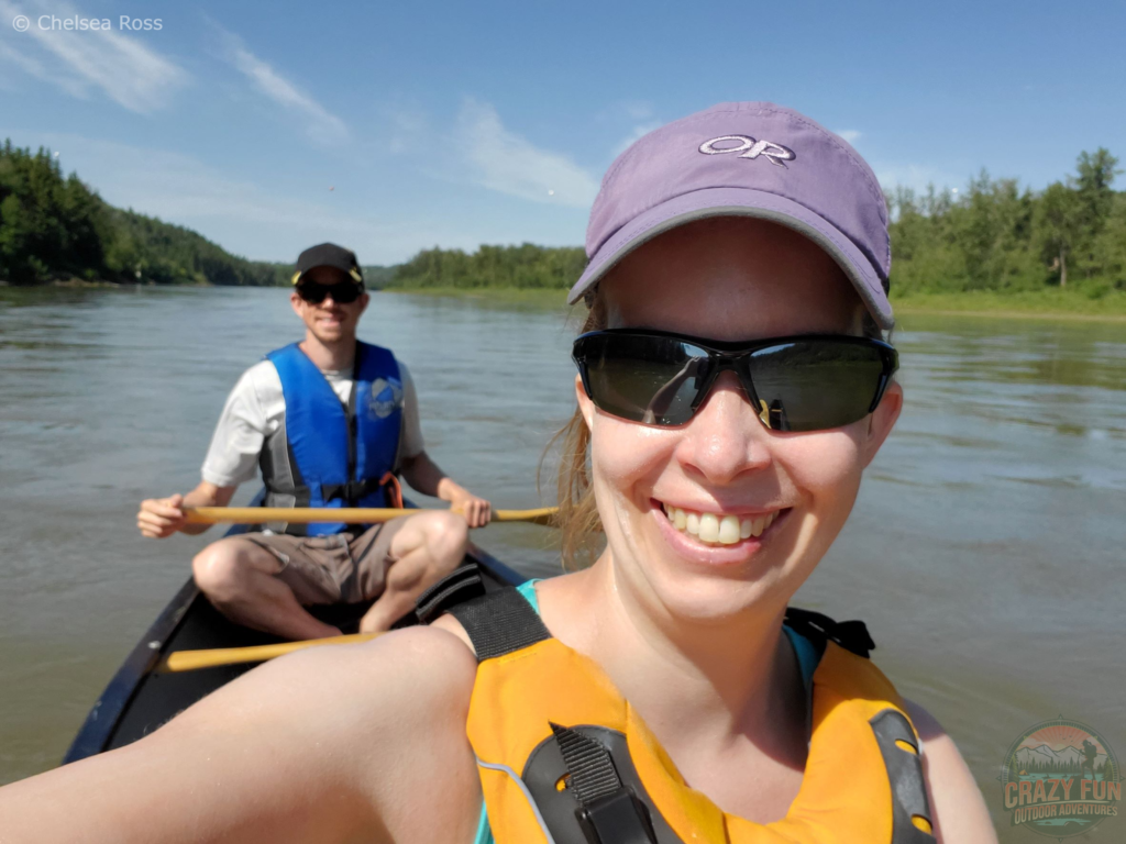 Edmonton Day Trips: Canoeing down the North Saskatchewan River. Scott in a white shirt, blue life jacket, black hat and sunglasses in the back. I'm wearing a yellow PFD with a purple hat and black sunglasses in front.