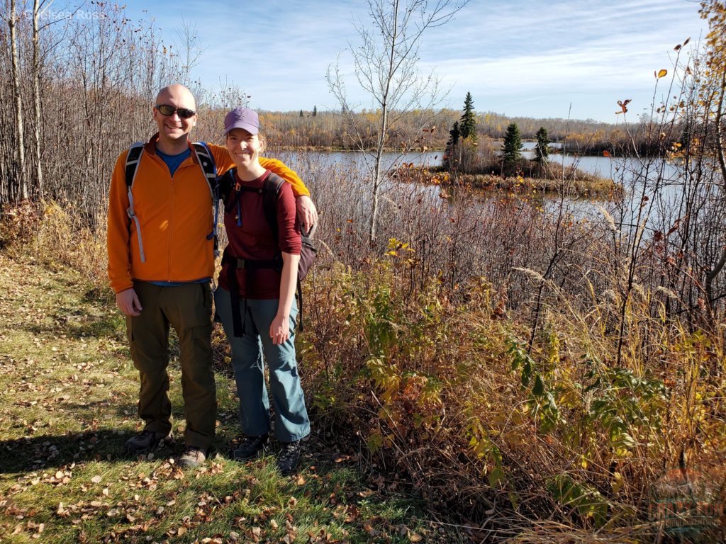 Edmonton Day Trips: Kris in a yellow fleece to the left with me in a red shirt to the right with a lake and yellow leaves behind us.