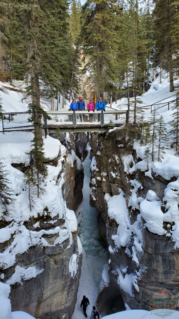 My family standing on a bridge with ice below them on the Maligne Canyon walk.