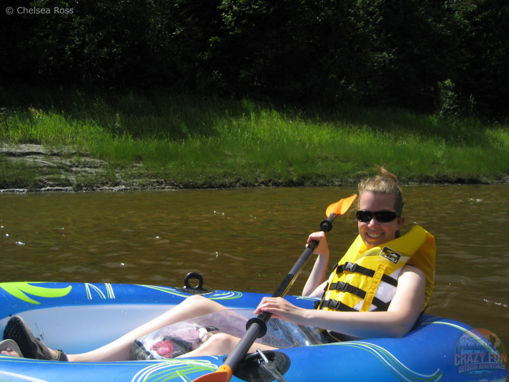 I'm having an Pembina River rafting day in the gorgeous Alberta heat. I'm sitting in my blue and white raft by myself on the water with my yellow lifejacket while holding my paddle with my clear bag between my legs. 