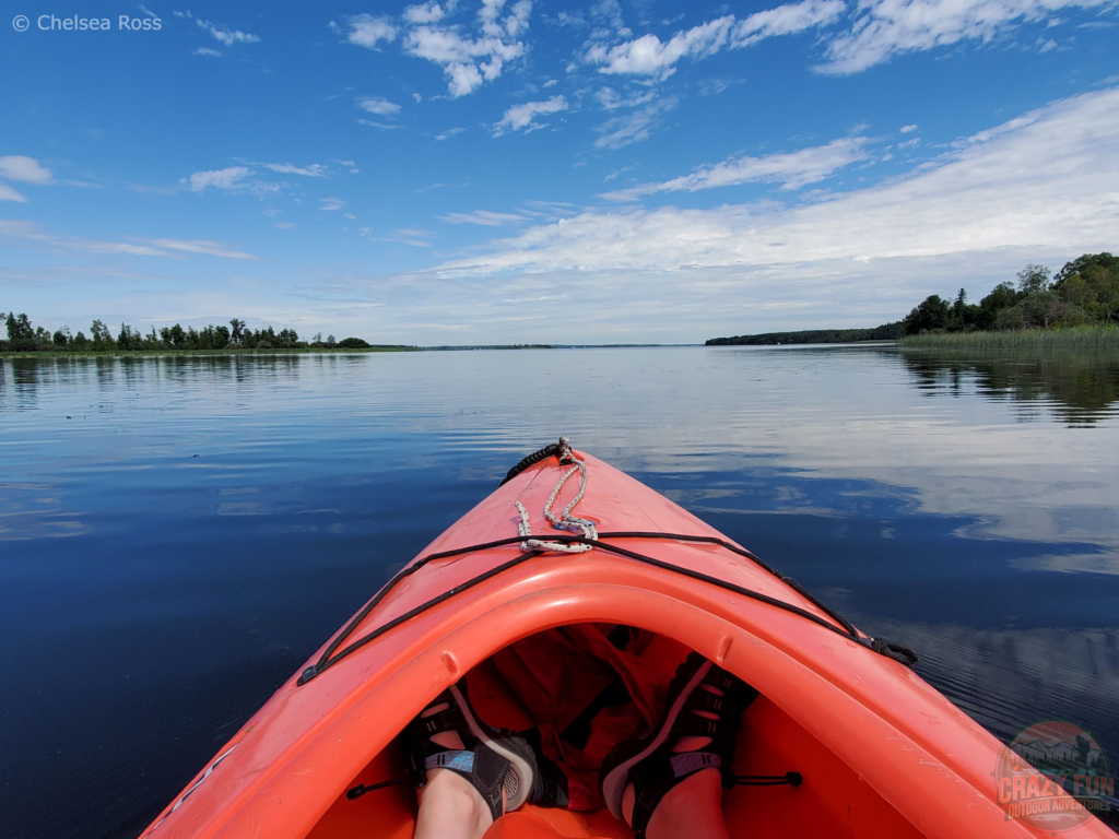 Keen Newport Sandals can be seen in a red kayak on the water. 