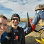 A selfie of Kris and I with a blue dinosaur in the background enjoying our Drumheller hikes.