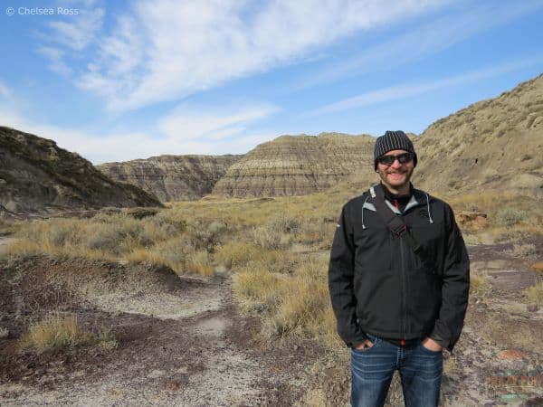 Man is on one of the best Drumheller hikes. You can see the canyon behind him.