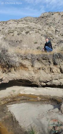 Lady crouching down on top of a creek bed.