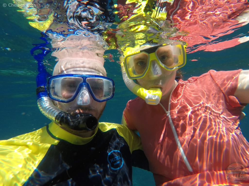 Snorkelling gear for beginners includes a mask and snorkel. Kris is in a yellow and black Lycra shirt on the left and I'm wearing a pink Lycra shirt. 