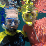 Snorkelling gear for beginners includes a mask and snorkel. Kris is in a yellow and black Lycra shirt on the left and I'm wearing a pink Lycra shirt.