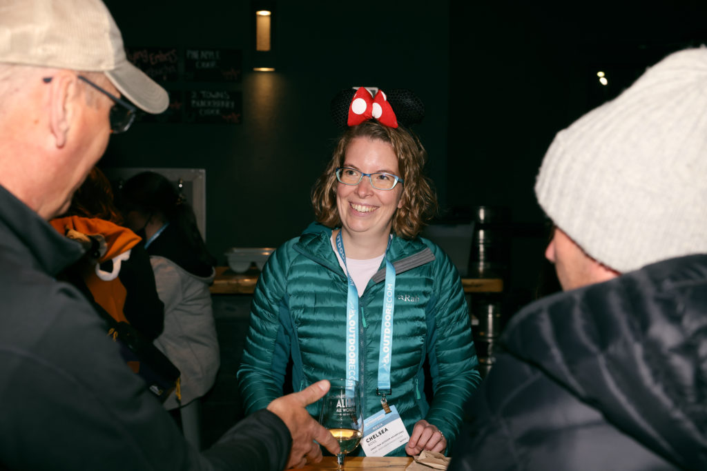 Networking at the Outdoor Media Summit at Alibi Ale. I'm wearing my Minnie mouse ears for Halloween with a green coat and lanyard. Two guys have the back of their heads in the picture.