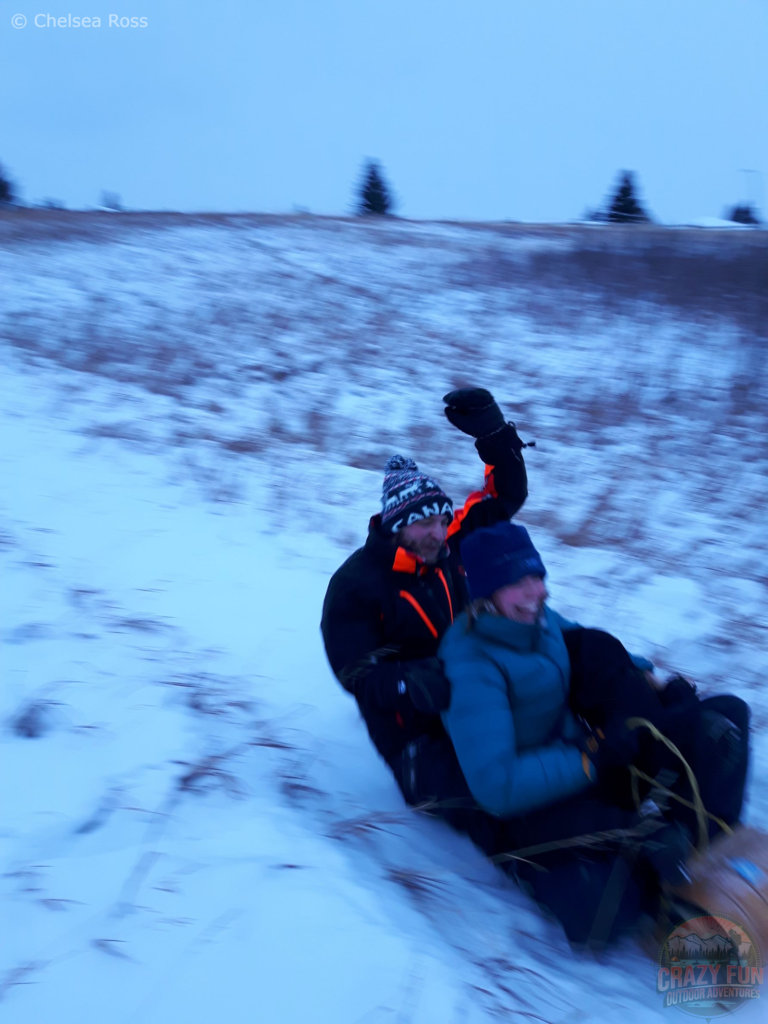 Kris and I sledding down the hill. Kris has his arm arm up and I'm laughing as we go down.