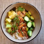 A picture of a shrimp veggie bowl with cucumbers, avocado, dill and pumpkin seeds.