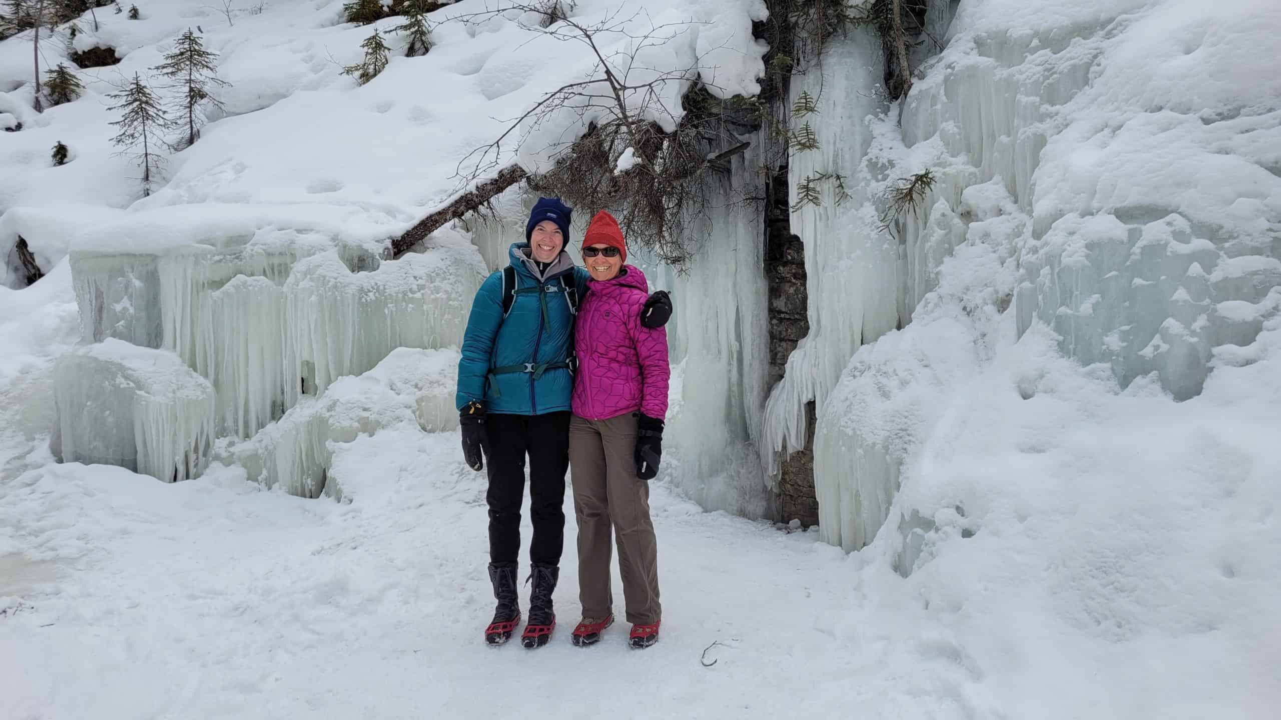Our testers standing in front of the iced over waterfall while wearing the Kahtoola Microspikes.