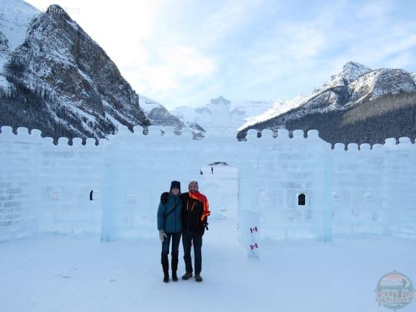 Couple standing in front of Lake Louise ice castle.