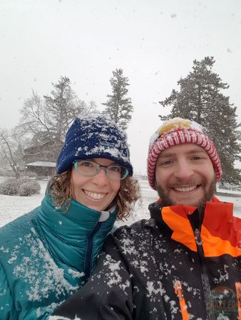 A selfie of a couple covered in snow walking in the town of Jasper. 