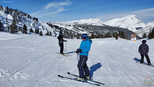 An adult is snowboarding in the background. 