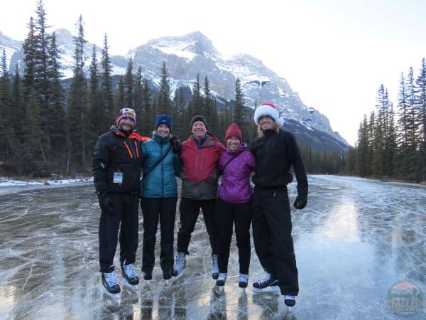 A family skating on a lake near Banff with mountains behind.