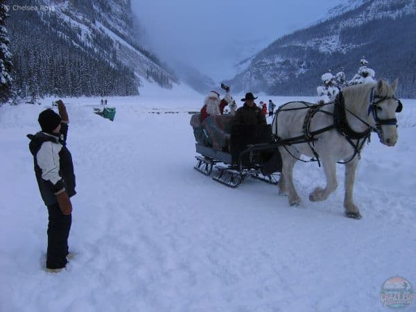 A lady waving to Santa going by on a sleigh.